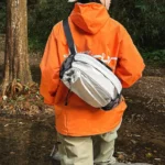 Sac banane en nylon gris clair porté en bandoulière dans le dos lors d'une randonnée en forêt