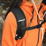 Sac banane à harnais noir porté par une femme en randonnée, vue rapprochée de la bretelle en maille alvéolée