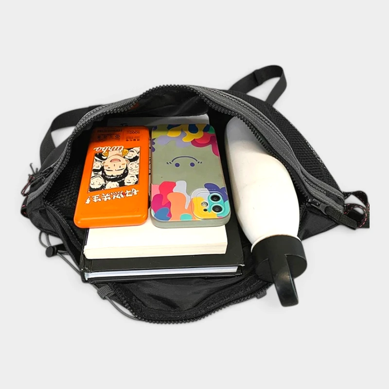 Sac banane noir ouvert vu de dessus avec une gourde et un smartphone rangés dans la poche principale