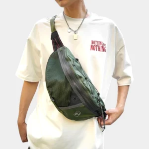 Sac banane vert kaki porté en bandoulière sur le torse par un homme de face avec poche avant en filet