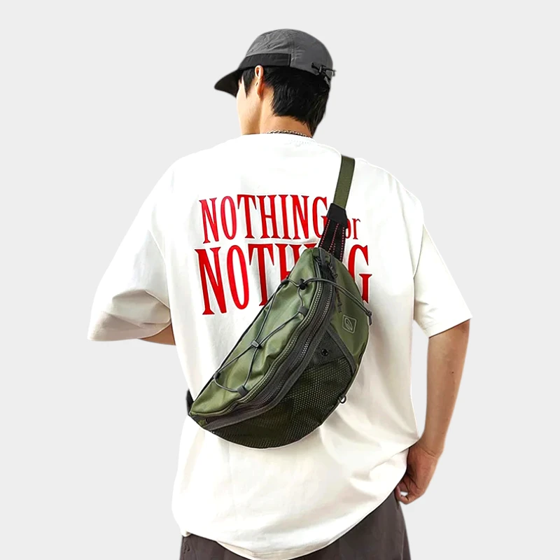 Sac banane vert kaki porté en bandoulière dans le dos par un homme vu de dos au style streetwear