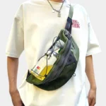 Grand Sac Banane Streetwear Nylon Poche Filet Sac banane vert kaki porté en bandoulière par un homme avec une bouteille d'eau tenue sous le cordon élastique