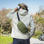 Sac banane vert kaki à quadrillage porté en bandoulière dans le dos par un homme lors d'une sortie en pleine nature