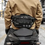 Grand Sac Banane Tactique Armée Velcro MOLLE Sac banane tactique en nylon camouflage sombre porté à la taille dans le dos par un motard sur sa moto