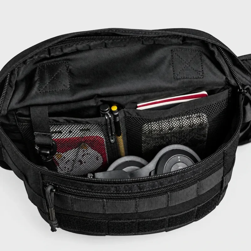Sac banane tactique en nylon noir ouvert avec poches intérieures en filet garnies d'un casque audio et de stylos
