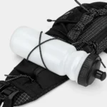 Sac banane noir en ripstop quadrillé posé à plat avec une gourde maintenue par un cordon élastique croisé