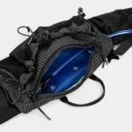 Sac banane noir en ripstop quadrillé ouvert sur sa poche principale contenant une poche à eau