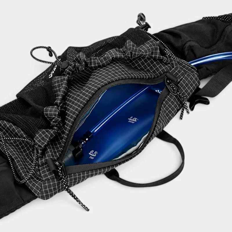 Sac banane noir en ripstop quadrillé ouvert sur sa poche principale contenant une poche à eau