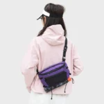 Sac Banane Trekking Imperméable Accrochable Sac banane ripstop violet porté en bandoulière dans le dos par une femme avec un parapluie fixé dessous