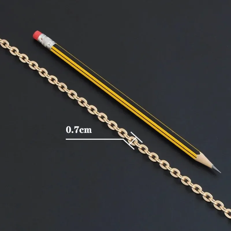 Bandoulière Chaine Dorée Sac avec maillons ovales aplatis et finition lisse, posée sur fond noir