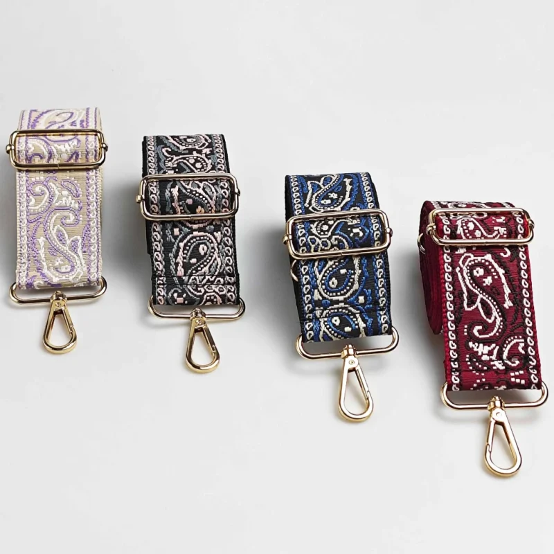 Bandoulière large paisley bandana en polyester jacquard déclinée en quatre coloris avec mousquetons et boucles de réglage dorés, posée de face