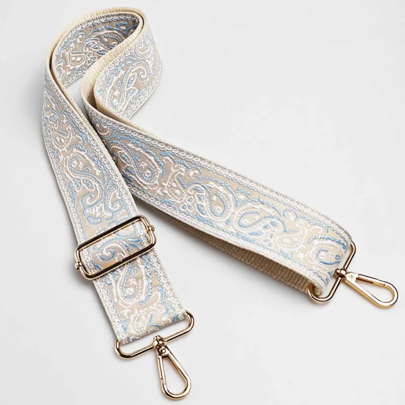Bandoulière large réglable motif paisley beige et bleu posée à plat avec mousquetons et boucle de réglage en métal doré
