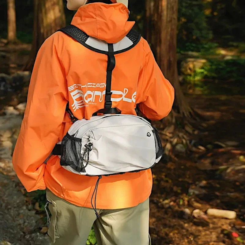 Sac banane en nylon gris clair porté dans le bas du dos avec son harnais de poitrine lors d'une randonnée en forêt
