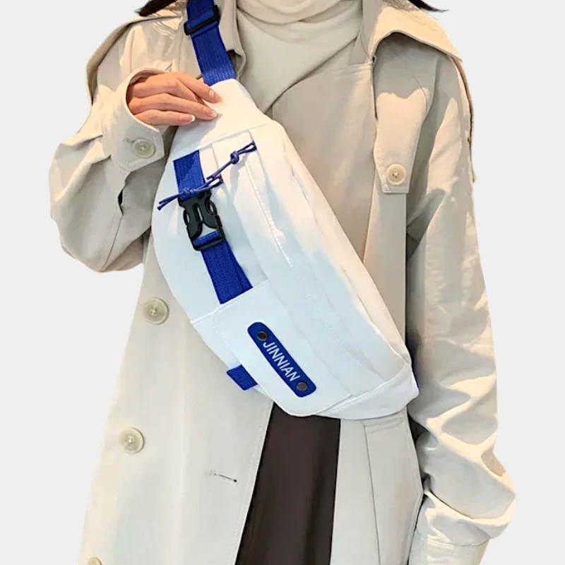 Sac banane techwear en nylon blanc porté en bandoulière sur la poitrine par une femme de face