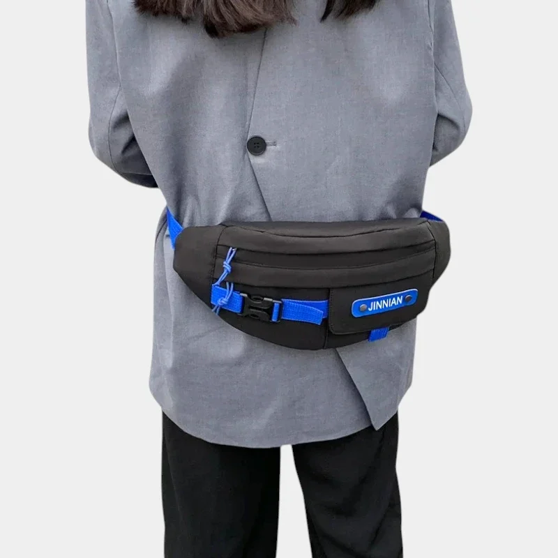Sac banane techwear en nylon noir porté à la taille dans le dos par une femme avec poche à rabat