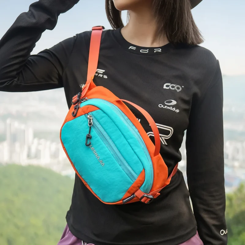 Femme portant un sac banane bicolore turquoise et orange en bandoulière sur la poitrine.