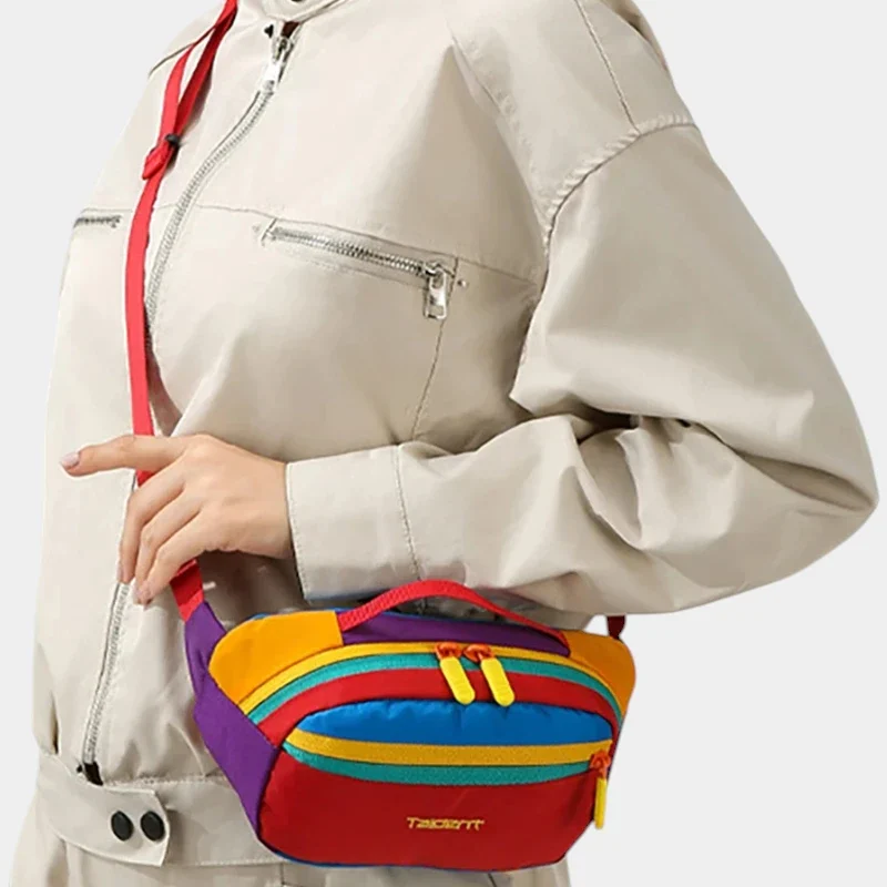 Sac banane colorblock multicolore en nylon porté en bandoulière par une femme au style casual-chic