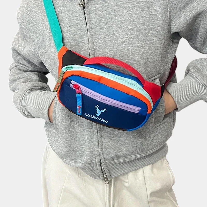 Petit sac banane nylon multicolore porté en bandoulière à la taille de face, au style streetwear colorblock