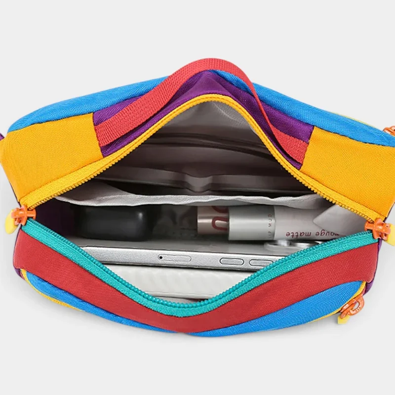 Sac banane colorblock en nylon vu de dessus, poche principale ouverte révélant un téléphone et un rouge à lèvres