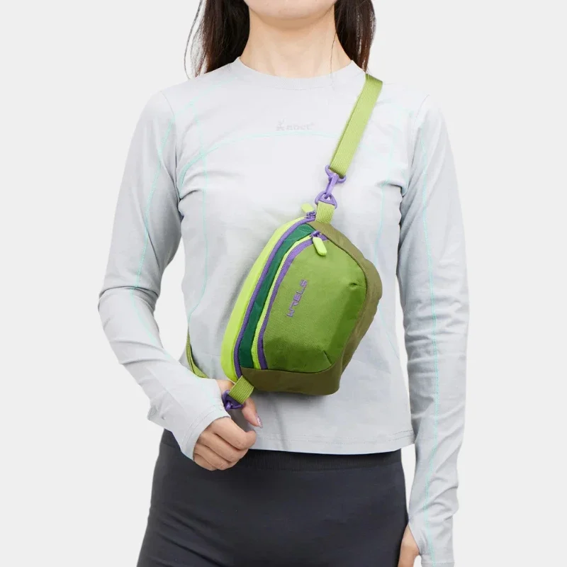Sac banane colorblock en nylon vert kaki et vert anis porté en bandoulière de face par une femme au style sportswear