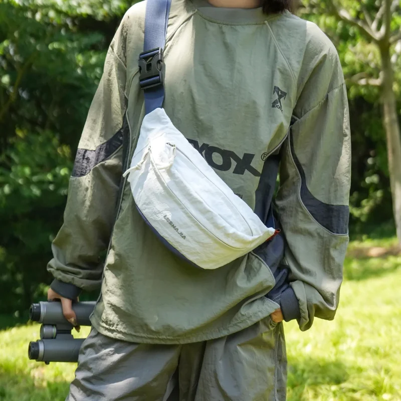 Sac banane coupe-vent années 90 blanc porté en bandoulière sur la poitrine par un promeneur en pleine nature