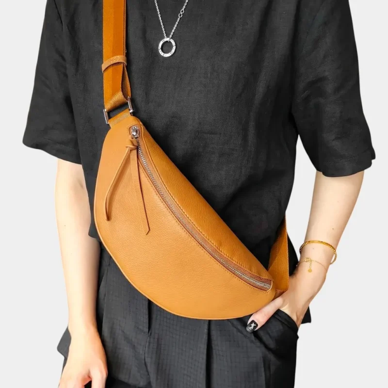 Sac banane cuir grainé camel porté en bandoulière par une femme, fermeture zippée avec languette