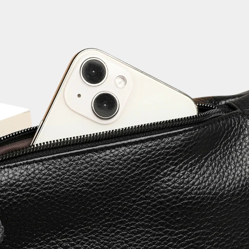 Sac banane en cuir grainé noir, gros plan sur la poche avant ouverte avec un iPhone glissé à l'intérieur