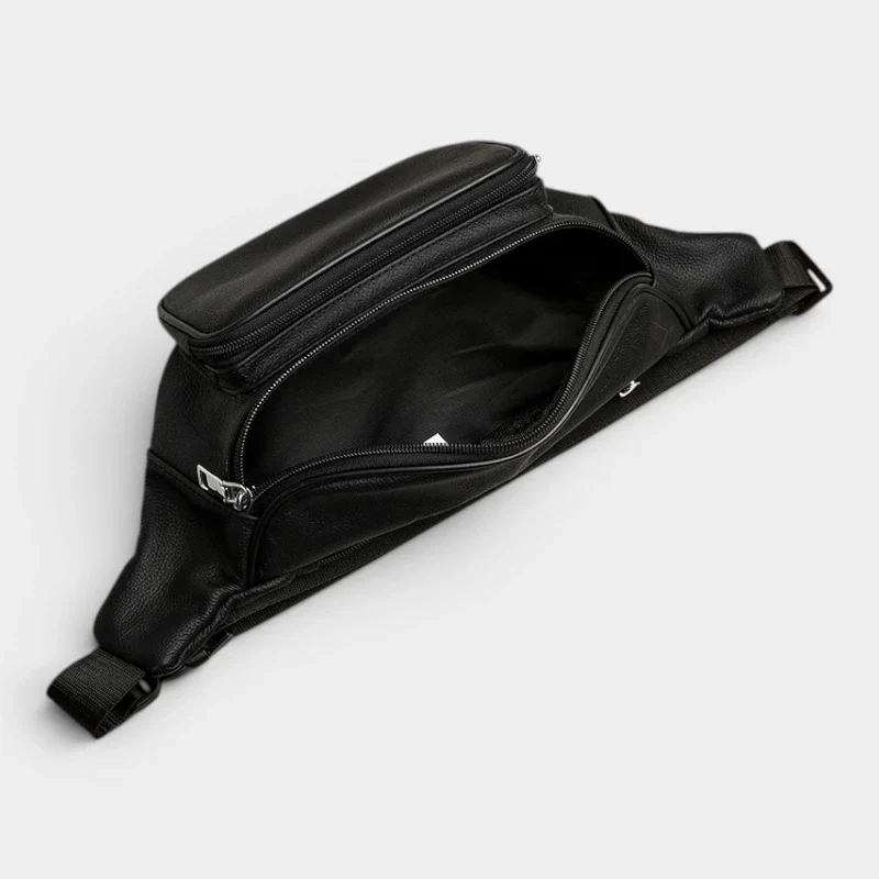 Sac banane en cuir grainé noir posé à plat, poche principale ouverte révélant une poche zippée intérieure