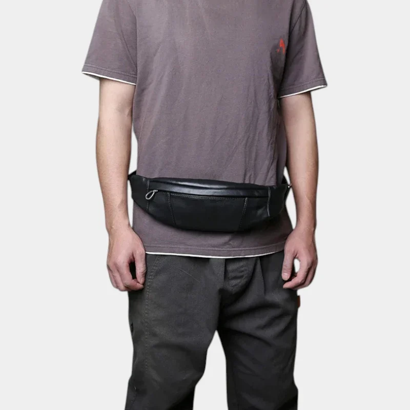 Petit sac banane cuir noir porté à la taille par un homme de face