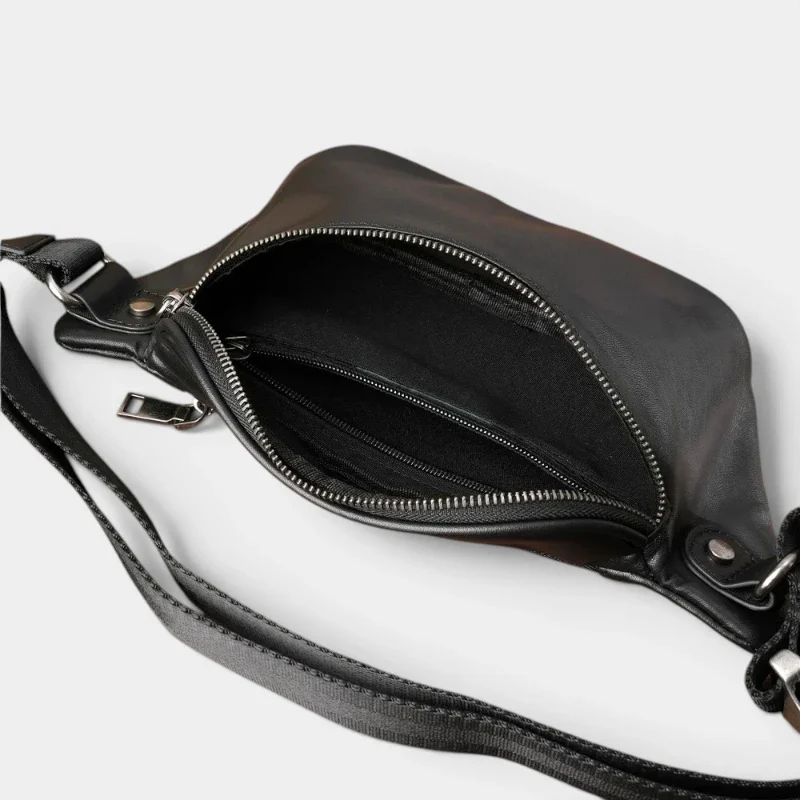 Sac banane cuir noir posé vu de dessus, poche principale ouverte révélant poches zippées intérieures