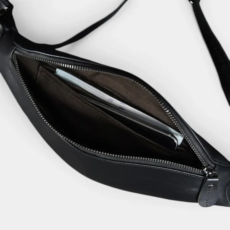 Petit sac banane cuir noir vu de dessus, poche principale ouverte contenant un smartphone