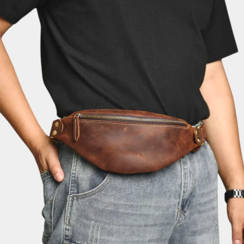 Petit sac banane cuir marron porté à la taille par un homme, fermeture zippée apparente