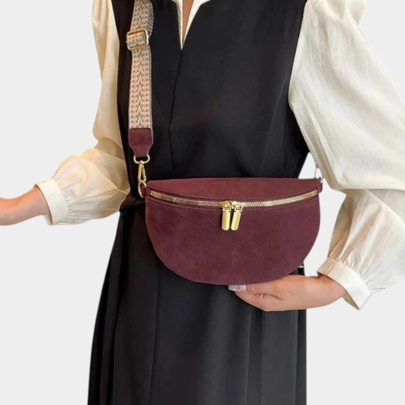 Sac banane simili cuir bordeaux porté en bandoulière par une femme avec sangle à motif tressé et zip doré