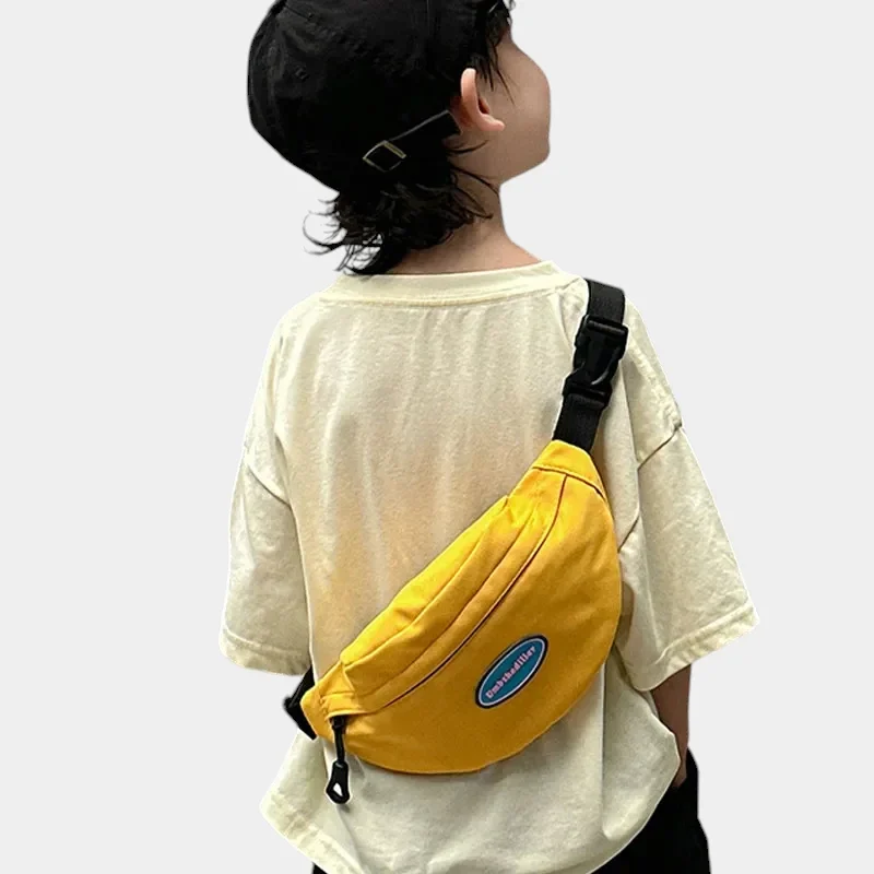 Sac banane enfant en toile de nylon jaune porté en bandoulière dans le dos par un petit garçon vu de dos