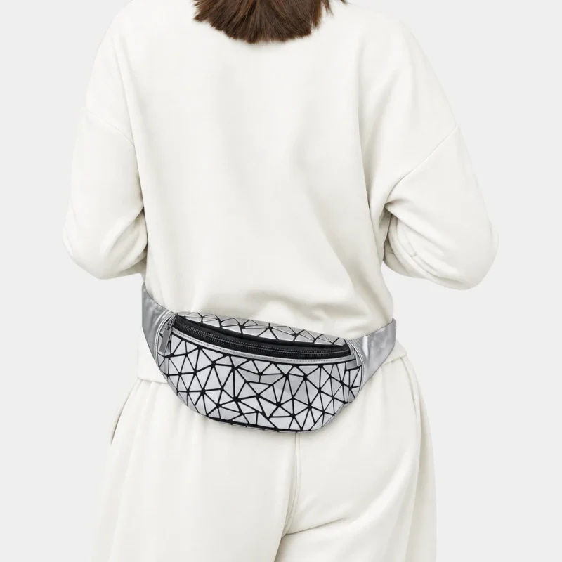 Sac banane argenté métallique en PVC à motif géométrique porté dans le dos par une femme au style sport-chic
