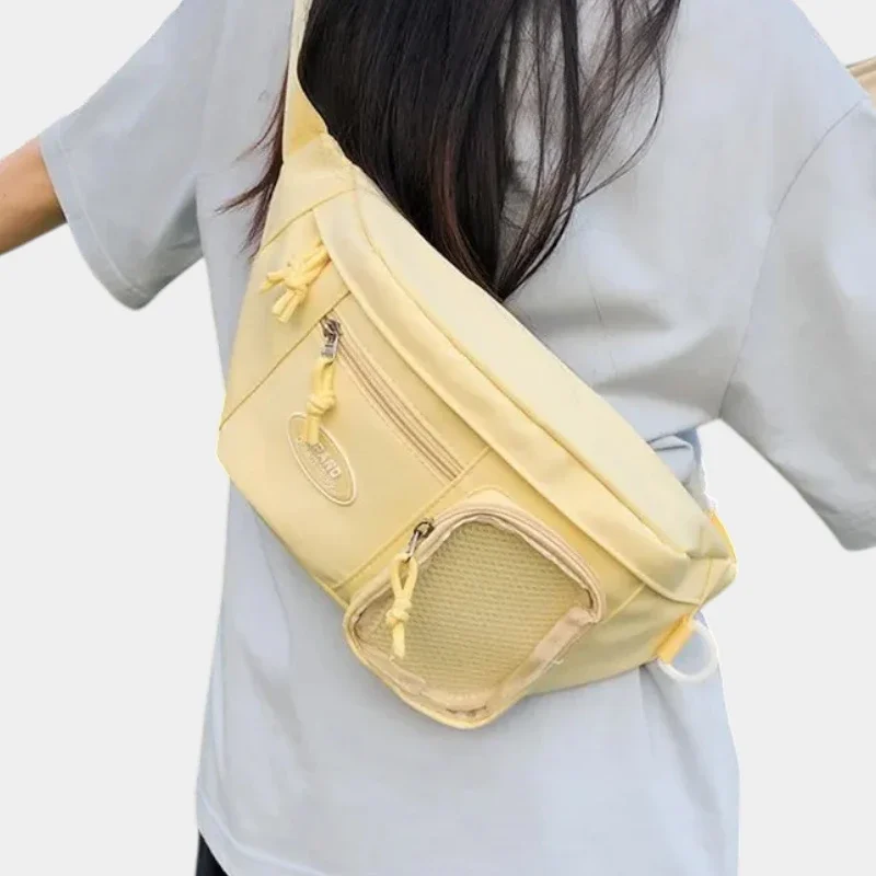 Grand sac banane femme en nylon jaune pastel porté en bandoulière dans le dos par une femme au style décontracté-chic