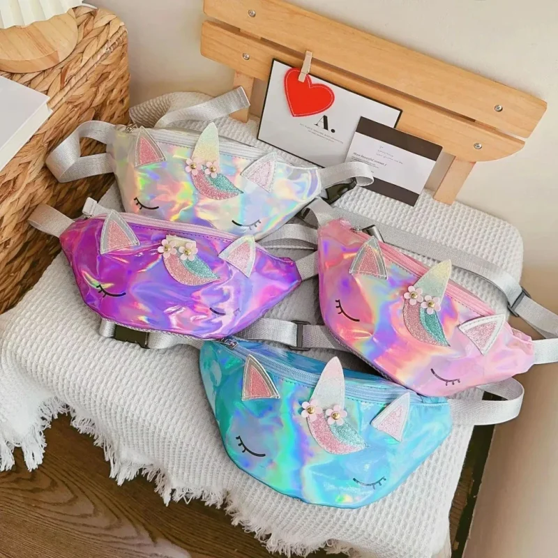 Sacs banane licorne holographiques blanc nacré, violet, rose et turquoise posés ensemble sur un plaid gaufré