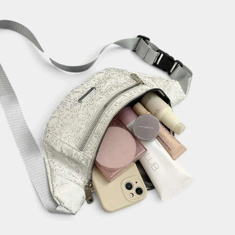 Sac banane demi-lune blanc ouvert sur sa poche principale avec un smartphone et du maquillage