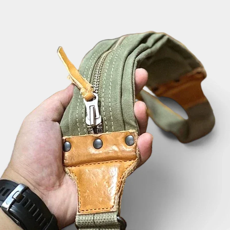 Sac banane kaki en coton et cuir porté en main par un homme, gros plan sur la fermeture à glissière métallique