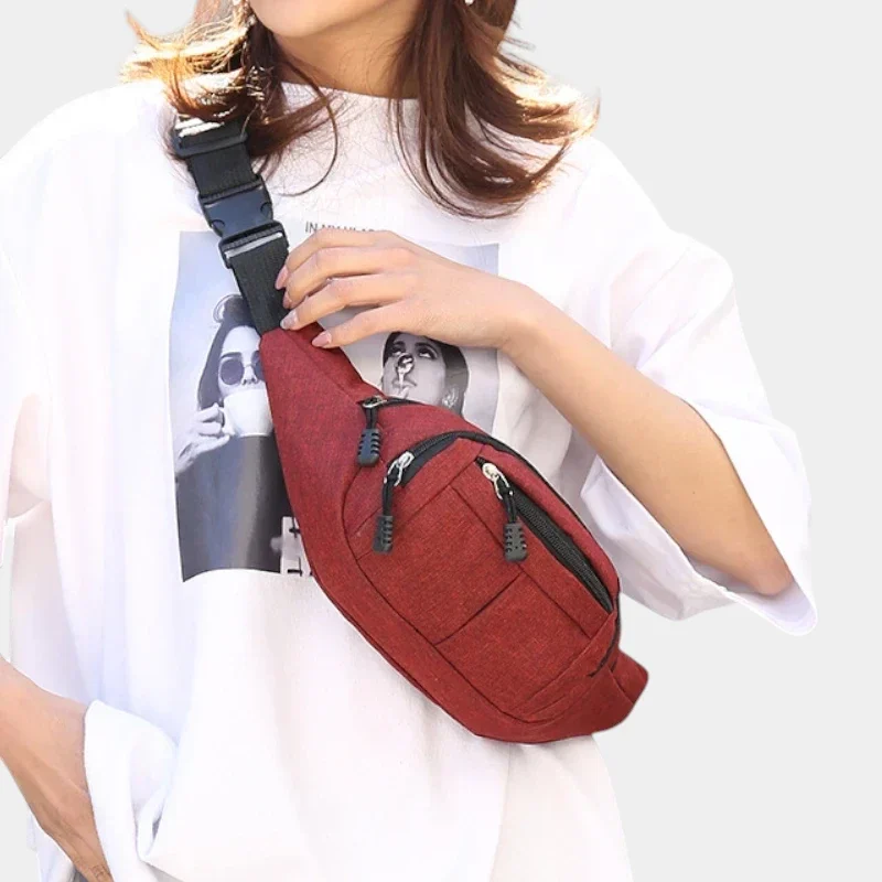 Sac banane en nylon rouge porté en bandoulière croisée par une femme au style casual-chic oversize, vue de face