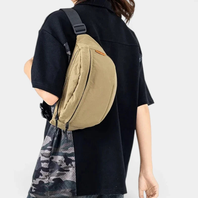 Sac banane nylon beige porté en bandoulière dans le dos par une femme au style streetwear
