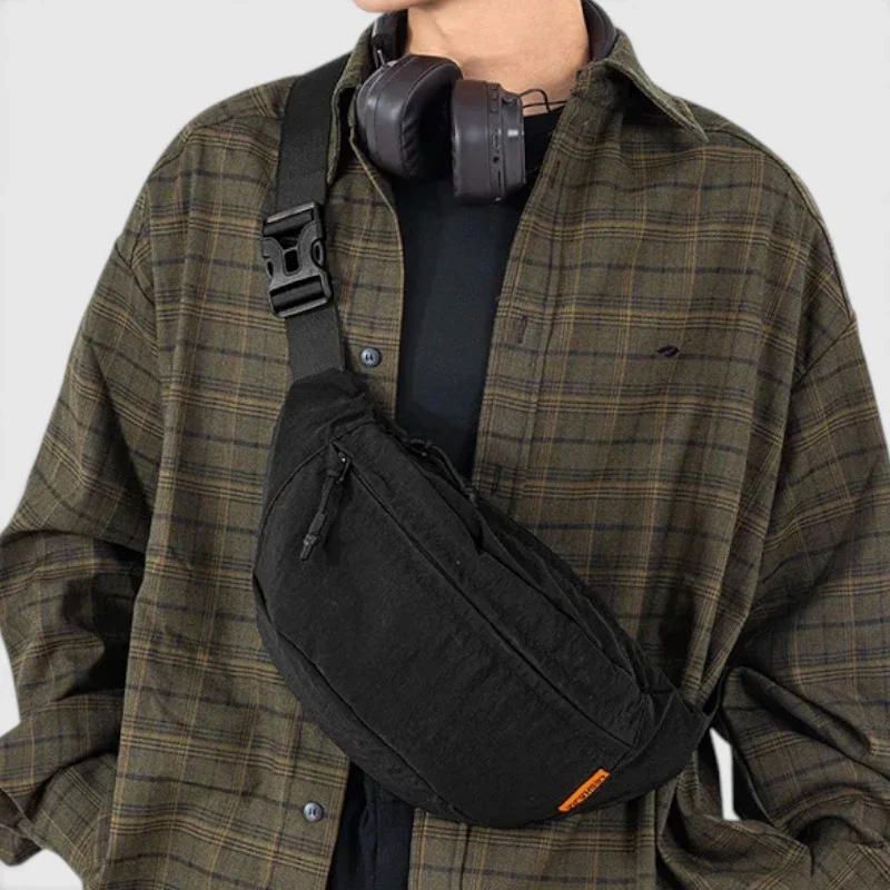 Sac banane nylon noir porté en bandoulière croisée par un homme au style streetwear décontracté