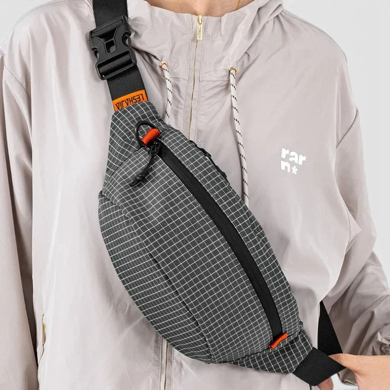 Sac banane nylon à carreaux gris porté en bandoulière croisée par une femme au style streetwear urbain-outdoor