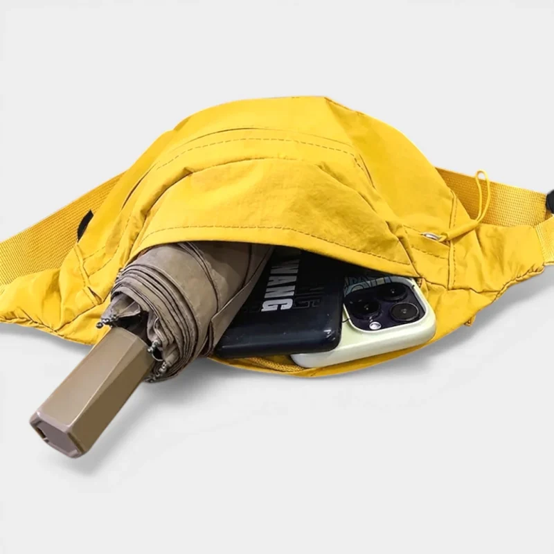 Sac banane jaune présenté de face, poche principale ouverte contenant un parapluie et un smartphone