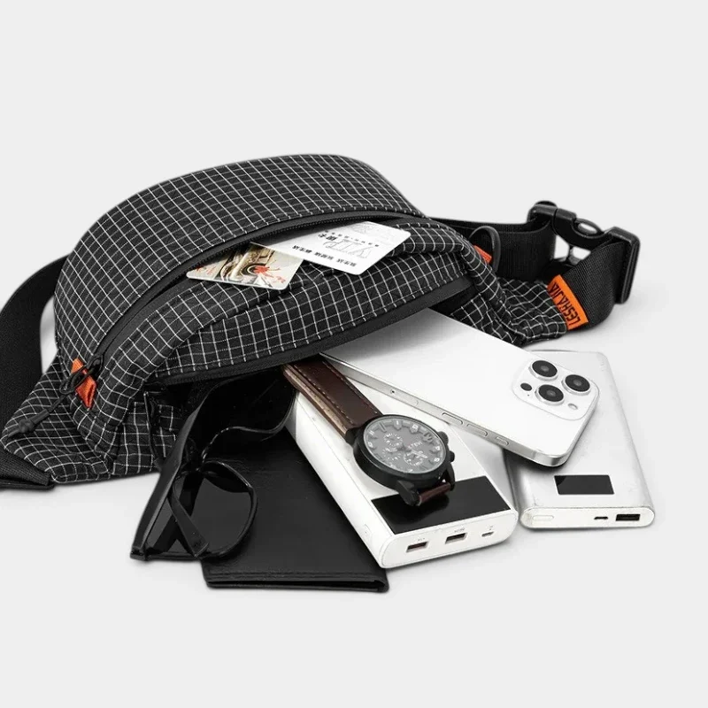 Sac banane nylon noir à carreaux, poche principale ouverte révélant un smartphone et une batterie externe