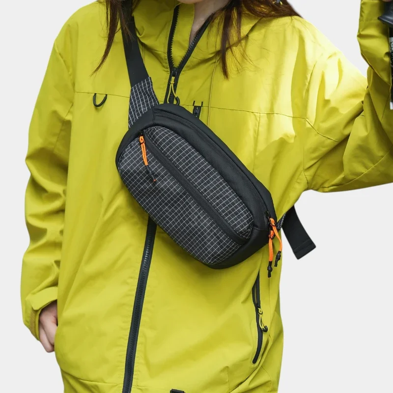 Sac banane nylon ripstop noir quadrillé porté en bandoulière par une femme au style outdoor streetwear