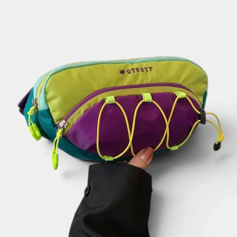 Sac banane outdoor multicolore vert, violet et turquoise, tenu à la main de face avec élastiques jaunes