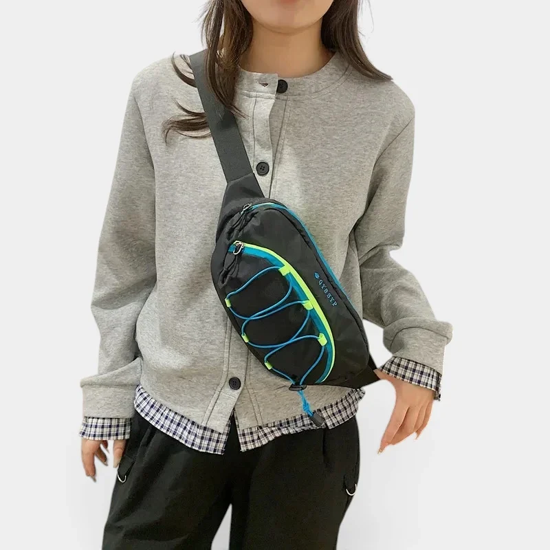 Sac banane outdoor noir porté en bandoulière croisée par une femme au style casual-chic avec des bandes élastiques colorées