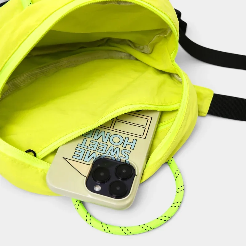 Sac banane nylon jaune fluo gorpcore, poche principale ouverte révélant une poche zippée intérieure et un smartphone