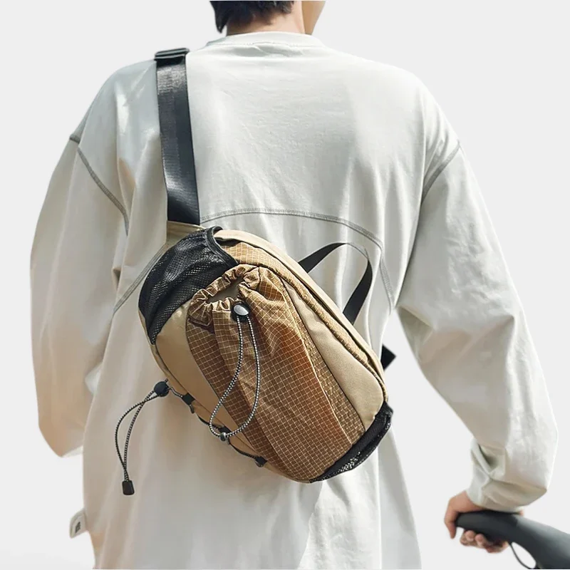 Grand sac banane randonnée en nylon beige quadrillé porté en bandoulière dans le dos par un homme de dos